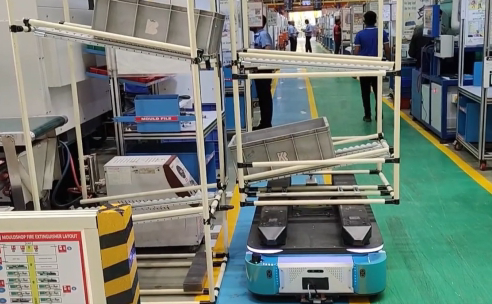 Autonomous mobile robot transporting a material rack in an industrial manufacturing facility.