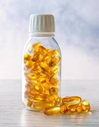 Clear plastic bottle containing golden softgel capsules with a white screw-cap closure.