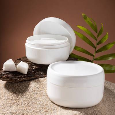 White cosmetic cream jars with flip-top and screw-cap closures displayed in a skincare product setting.